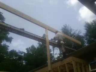 Carpenter setting a ridge beam over a new addition frame — Ice Dam Removal by Roofing Brothers in Wilkesboro