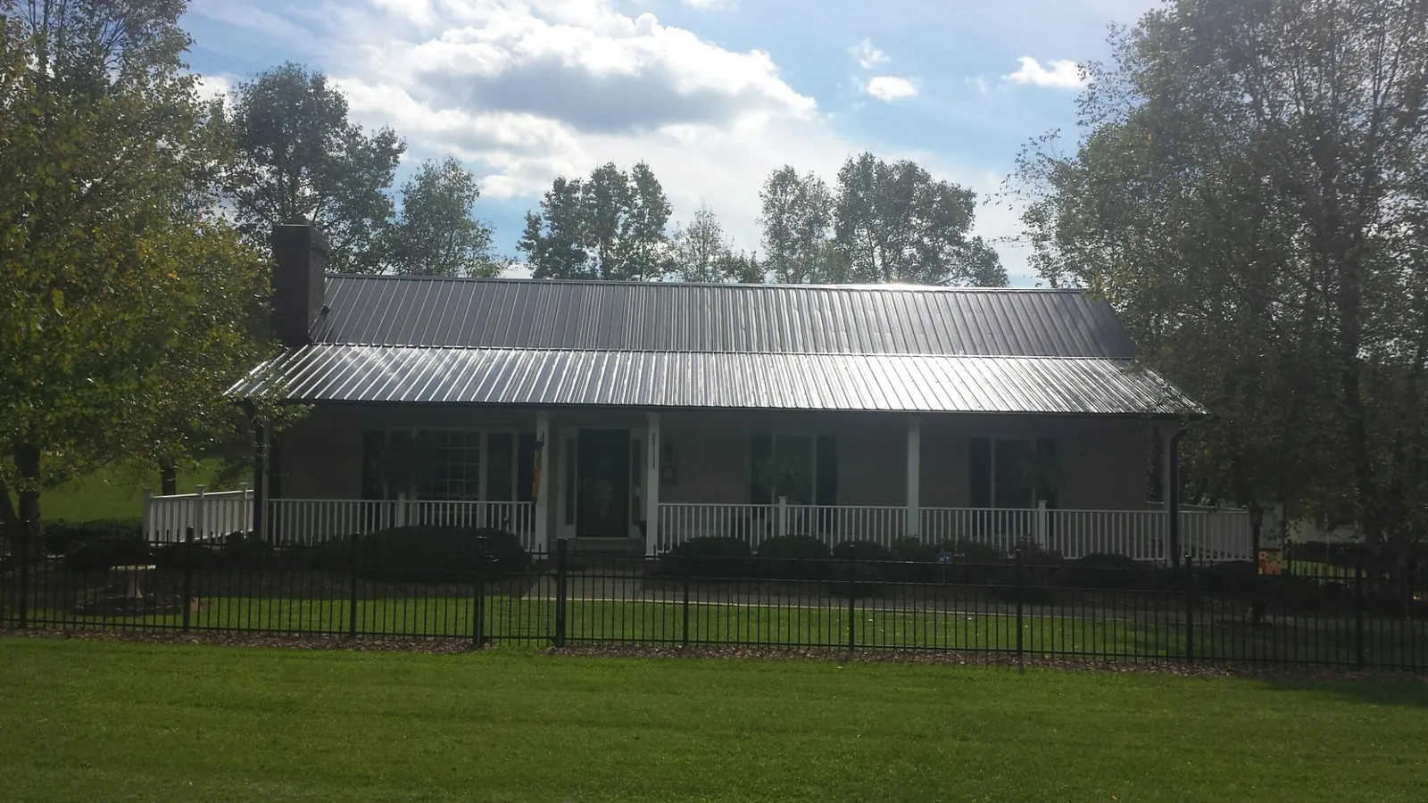Gray metal roof on a brick ranch with a full width front porch — Gutter Guard Installation work by our crew in Wilkesboro
