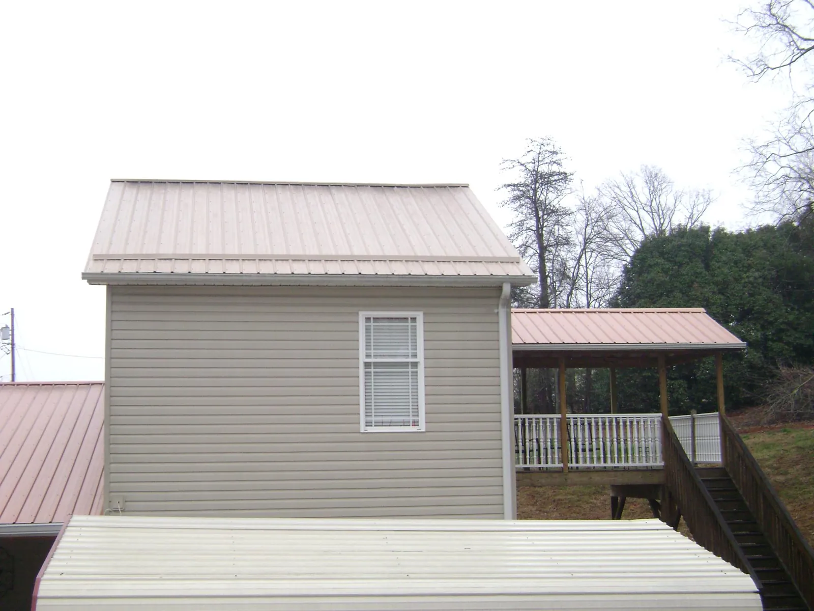 Tan metal roofs on a two story addition and attached porch, from a Roof Replacement job in Wilkesboro