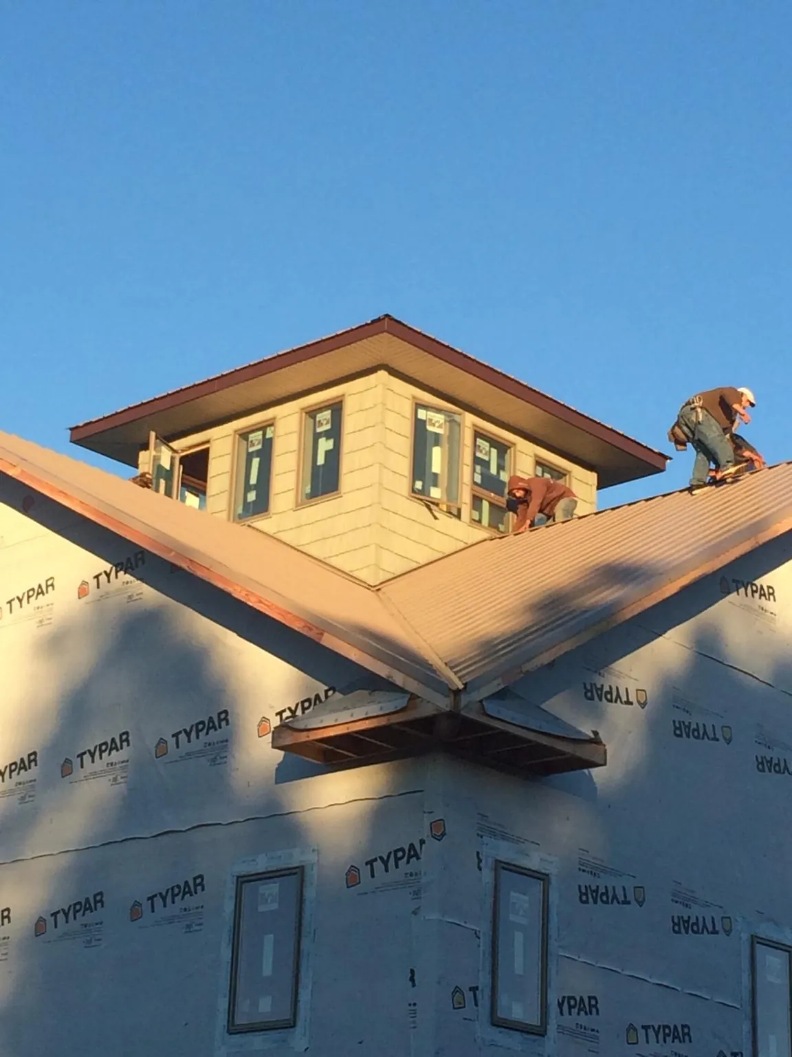 Roofers working around a rooftop cupola on a new metal roof at sunset — Roof Waterproofing in Wilkesboro by Roofing Brothers
